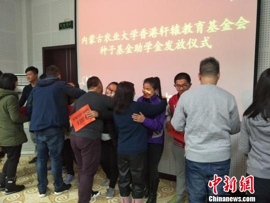 图为受资助的学生与帮助他们的人相拥 乌娅娜 摄